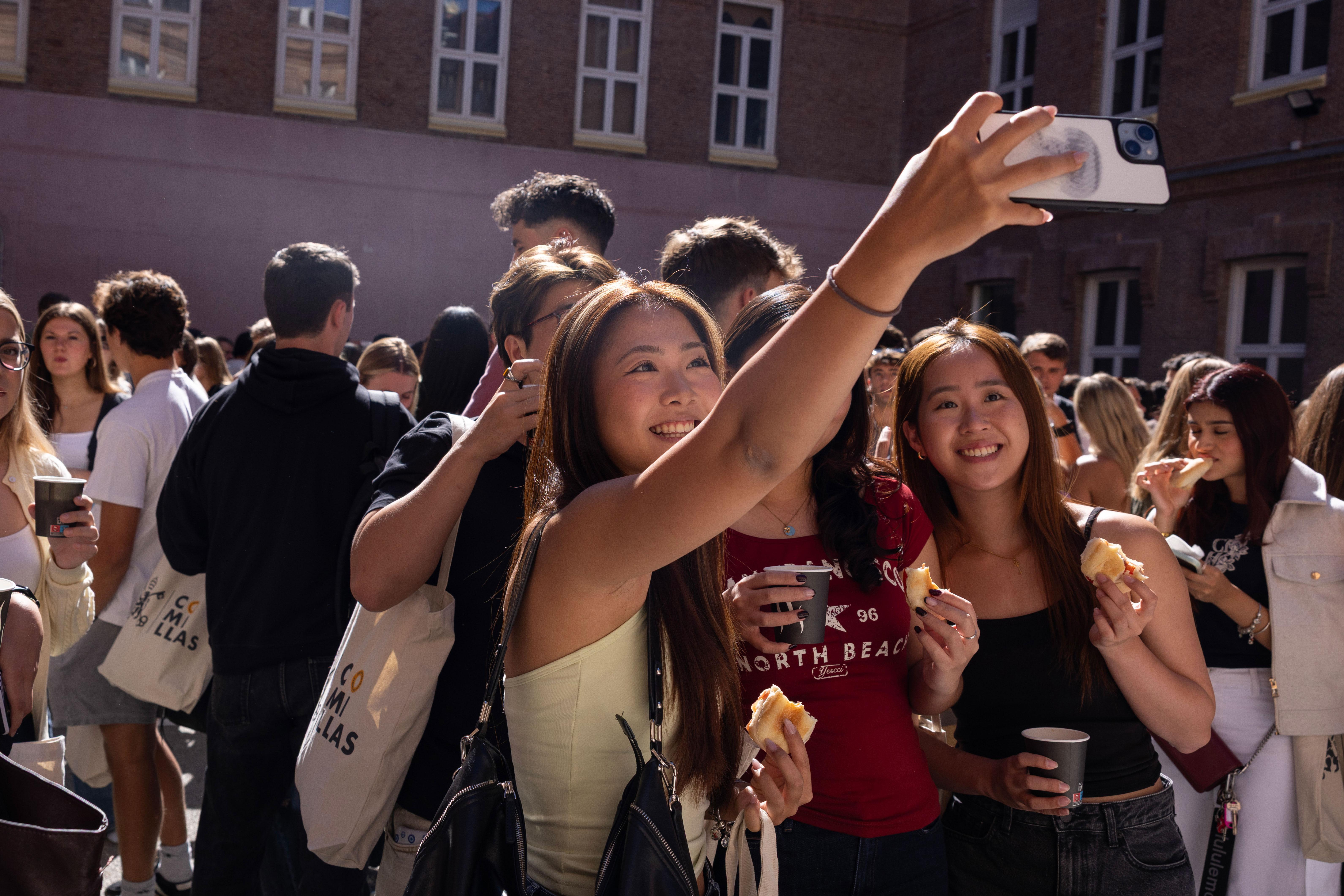 Un grupo de jóvenes sonrientes posando y tomando una selfie en un evento al aire libre.