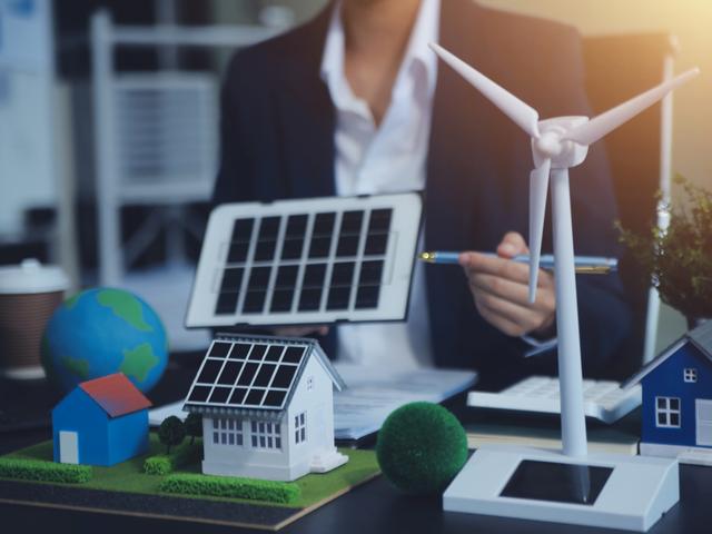Una persona muestra modelos de energías renovables en una mesa de trabajo.