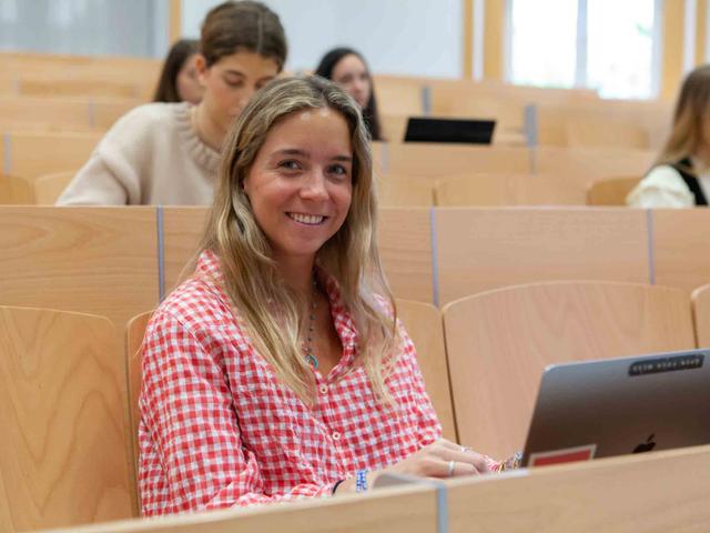 Alumna icade en clase sonriendo