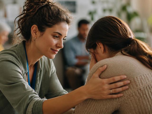Una mujer consolando a otra en un entorno de apoyo emocional.
