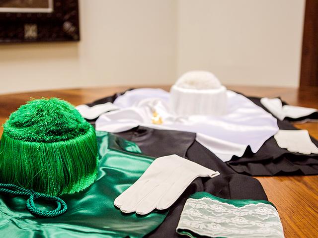 Uniformes académicos con gorros y guantes en tela, preparados para ceremonia en la Universidad de Comillas.
