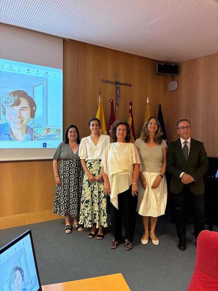 Grupo de personas posando para una foto en una sala de conferencias, con una presentación proyectada en la pared.