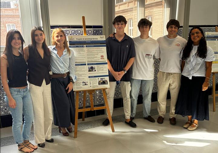 Un grupo de jóvenes se encuentra posando junto a un cartel en un espacio moderno.