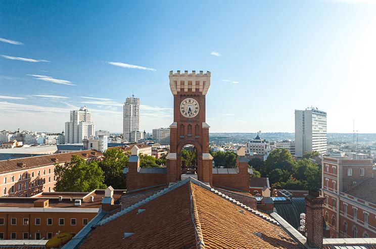 Vista de un paisaje urbano con un edificio histórico y un reloj en primer plano.