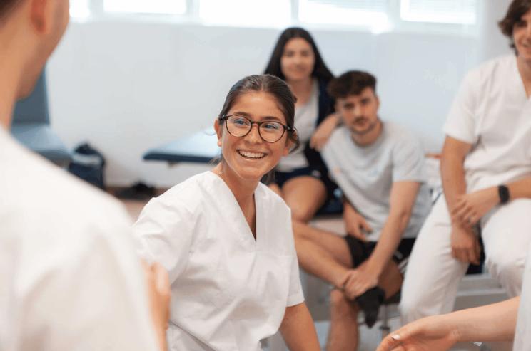 Un grupo de estudiantes en un ambiente académico, con una joven sonriendo en primer plano.