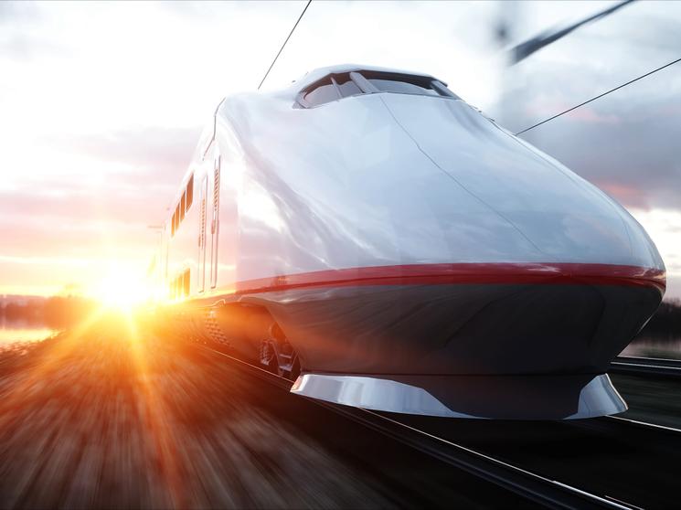 A high-speed train traveling at sunset with motion blur effect.