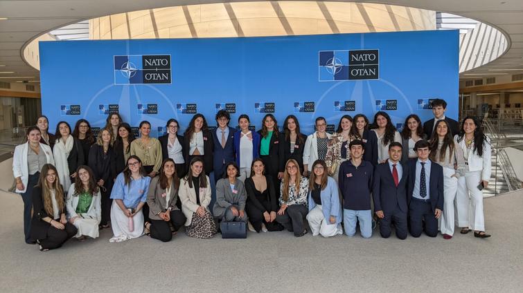 A group of young adults posing for a photo at a NATO event.