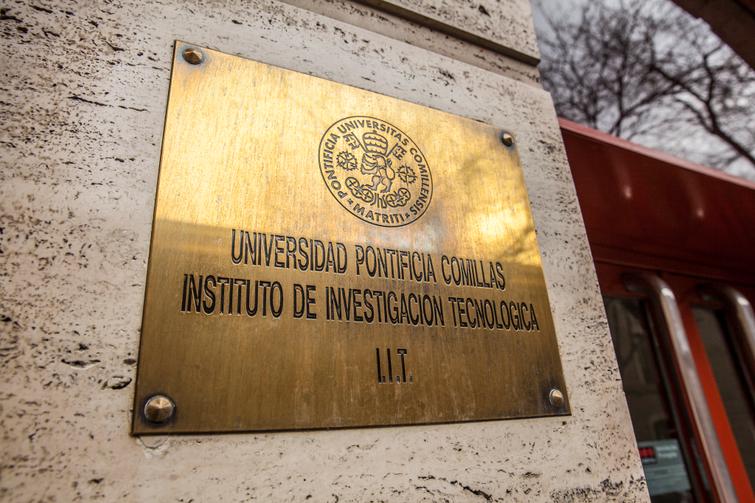 A brass plaque on a wall indicating 'Universidad Pontificia Comillas, Instituto de Investigación Tecnológica I.I.T.'