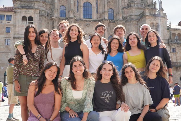 A group of diverse people smiling in front of a historic building with intricate architecture.