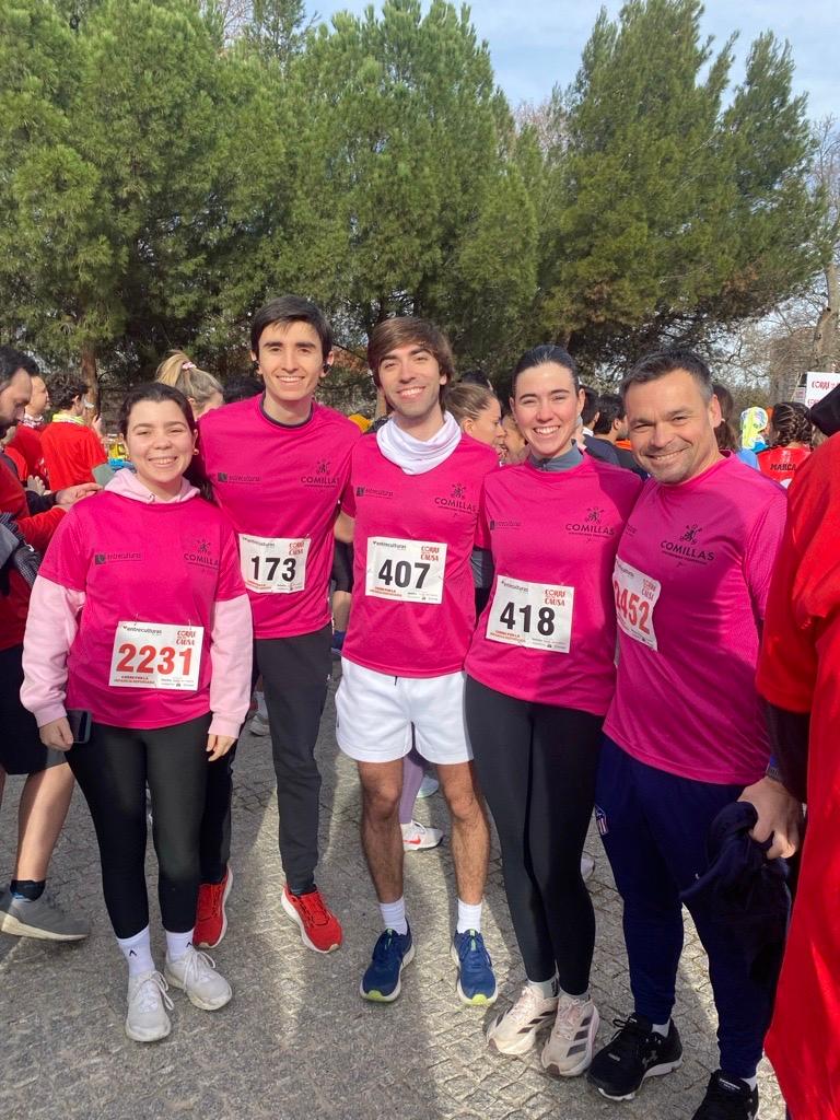 Un grupo de cinco personas posando sonrientes en un evento deportivo, todos vestían camisetas rosas y con números en el pecho.