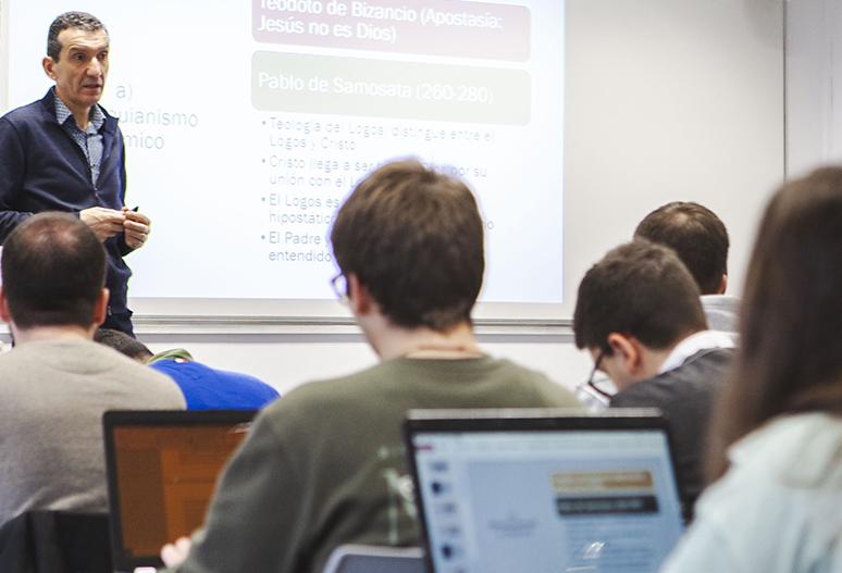 Una clase magistral en la que un profesor presenta información sobre la historia del cristianismo a un grupo de estudiantes.