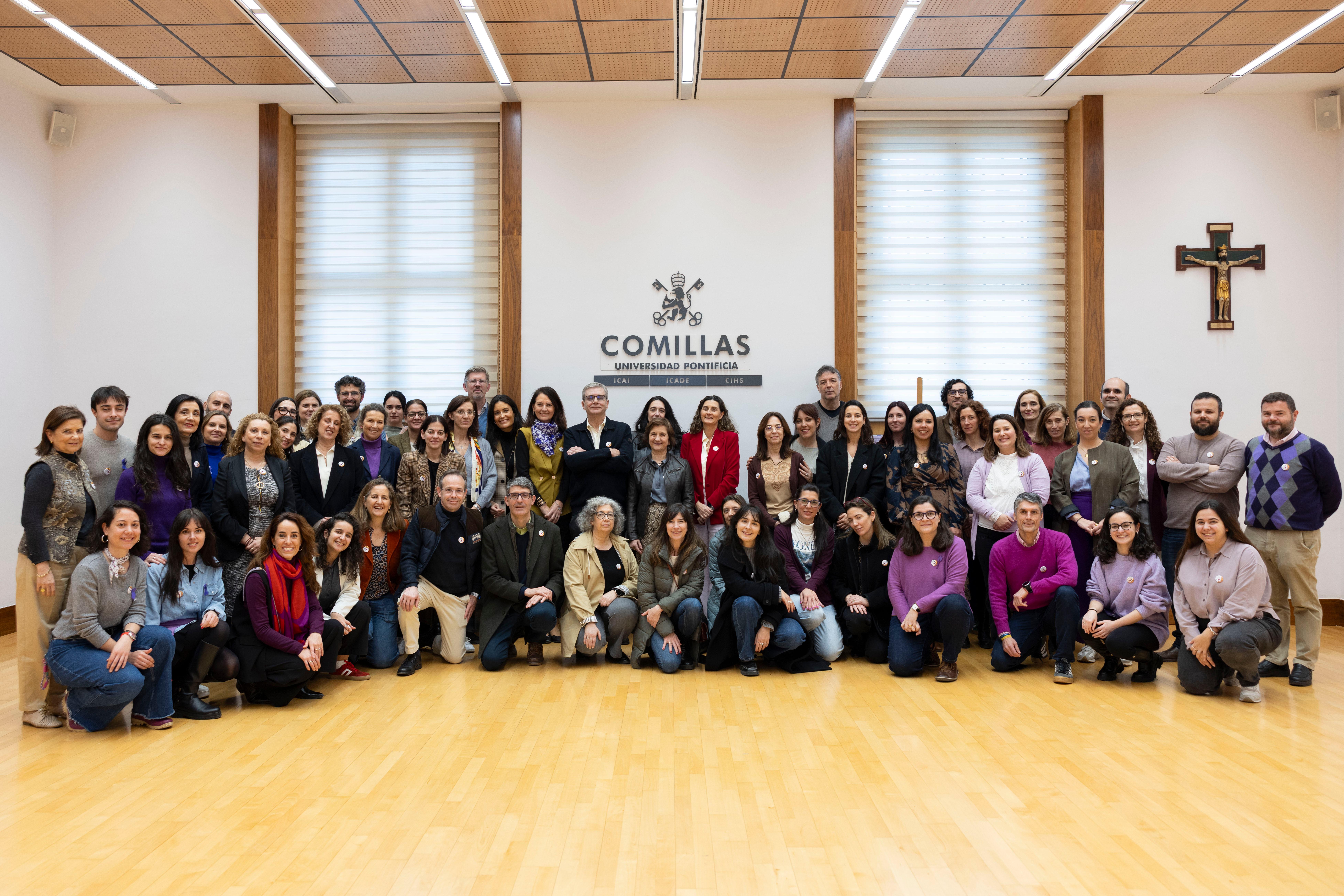 Un grupo de personas se reúne en un salón con un fondo que dice 'COMILLAS'.