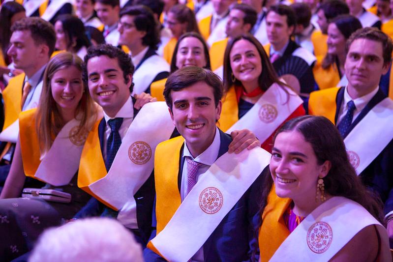 A group of smiling students wearing caps and gowns at a graduation ceremony.