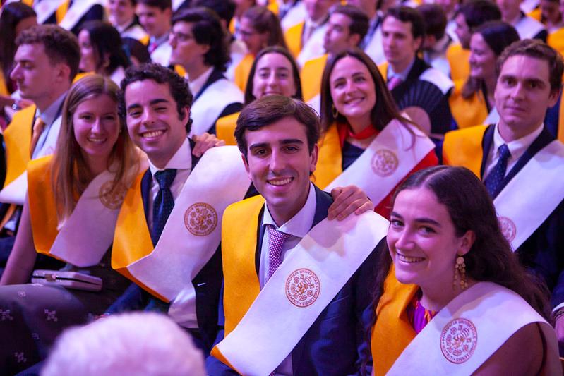 A group of smiling students wearing caps and gowns at a graduation ceremony.