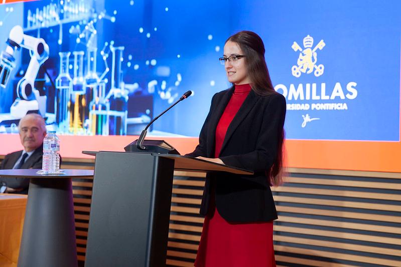 Una mujer está dando un discurso en un podio durante un evento en la Universidad Pontificia Comillas.