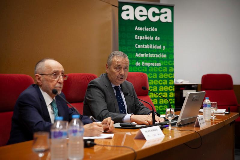 Dos hombres discuten en una mesa durante un evento organizado por la Asociación Española de Contabilidad y Administración de Empresas.