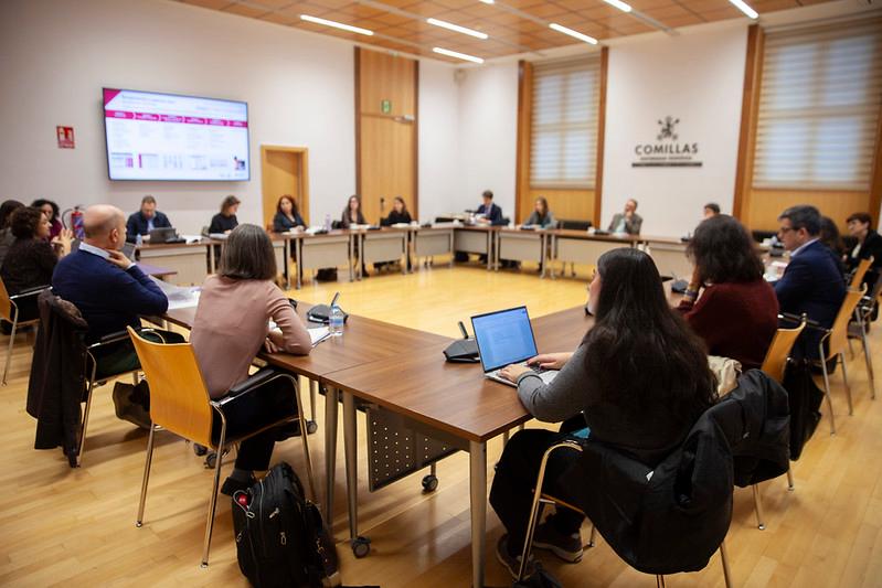Una reunión en una sala con varias personas sentadas alrededor de una mesa.