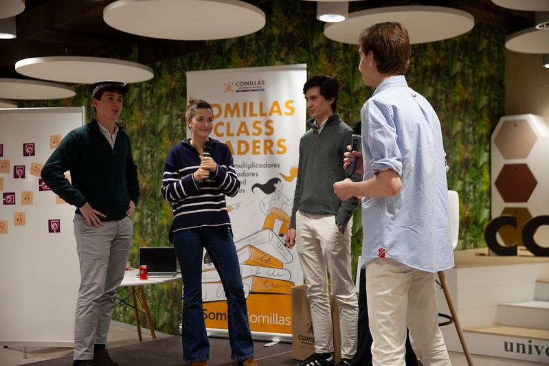 Un grupo de jóvenes interactúa en un evento de presentación en un ambiente moderno.
