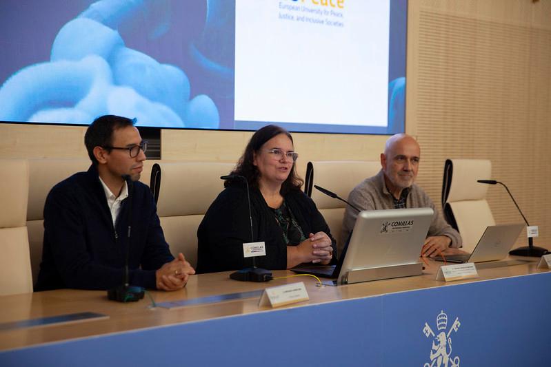 Tres personas sentadas frente a un panel en un evento o presentación.