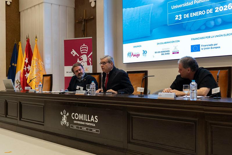 Una mesa redonda en la Universidad Pontificia Comillas con varios ponentes y banderas al fondo.