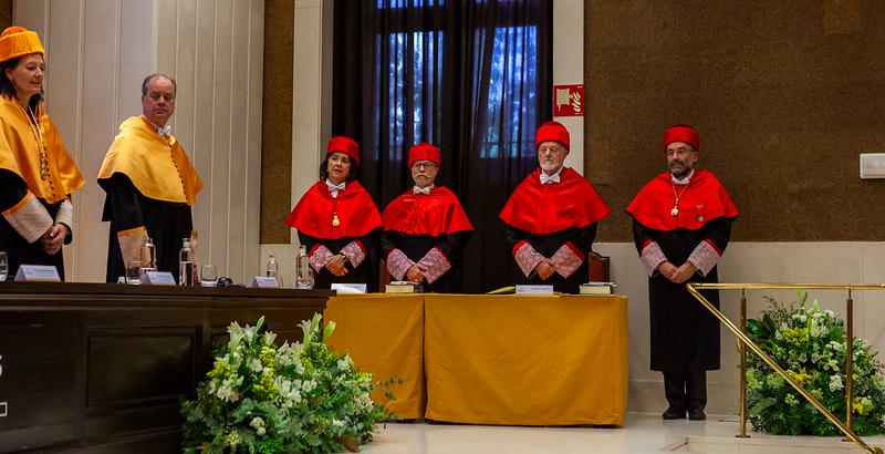 Grupo de personas en una ceremonia académica vestidas con togas ceremoniales de diferentes colores.