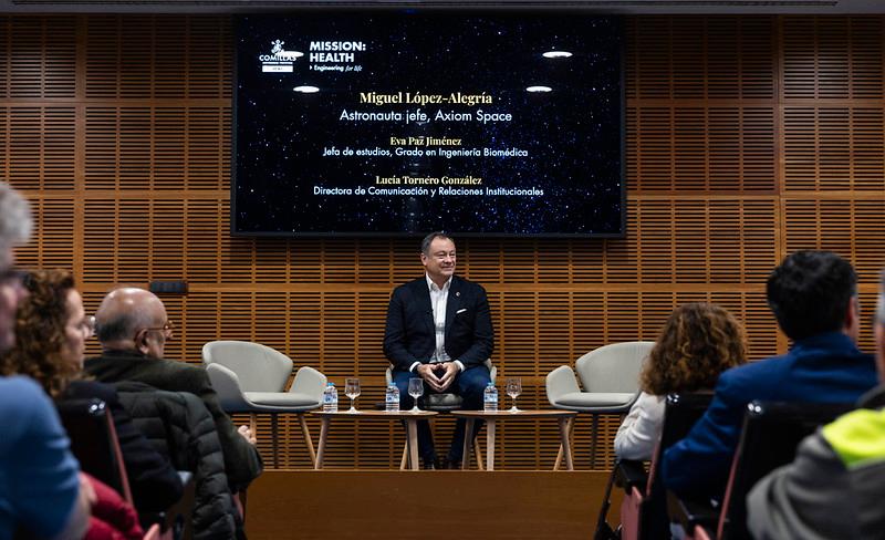 Un grupo de personas asiste a una charla con el astronauta Miguel López-Alegría en una sala moderna.