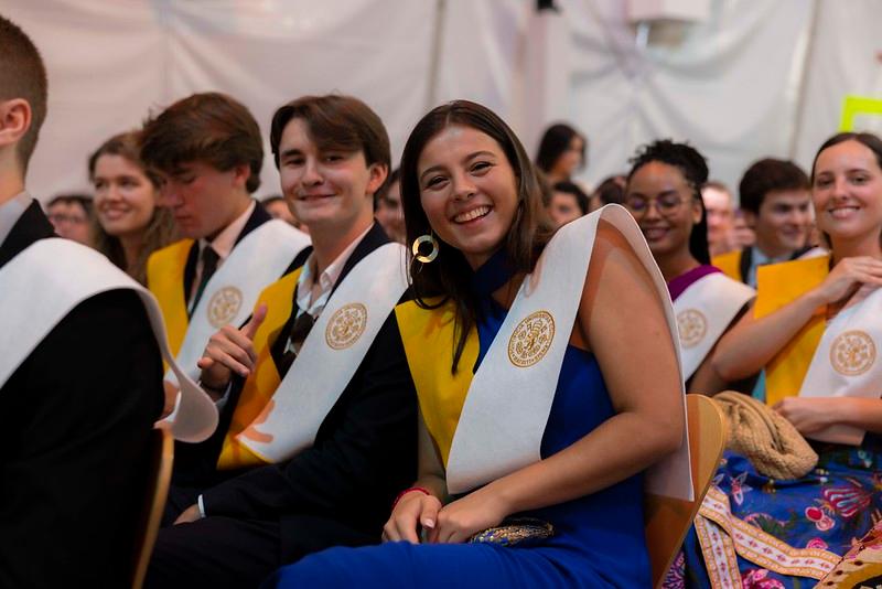 Un grupo de estudiantes sonrientes en una ceremonia de graduación, con togas y pañuelos distintivos.