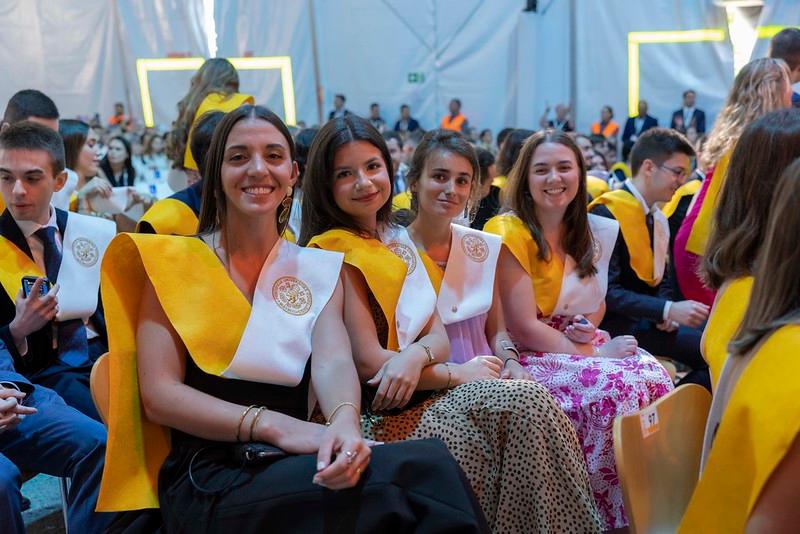 Un grupo de jóvenes sonríe mientras asisten a una ceremonia de graduación.