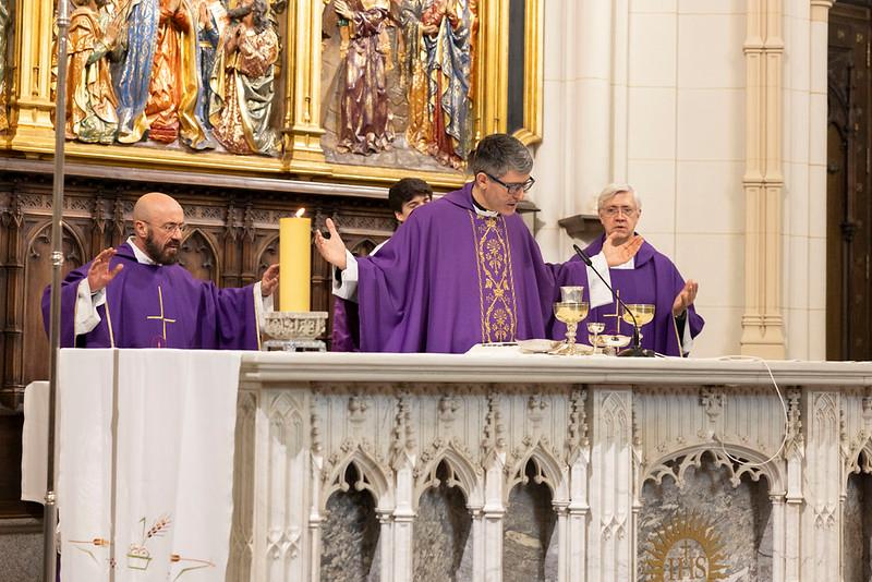 Celebración de una misa con tres personas en la mesa del altar.