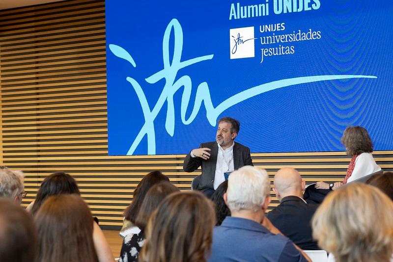 Un evento donde un ponente está hablando frente a un público en un ambiente moderno.