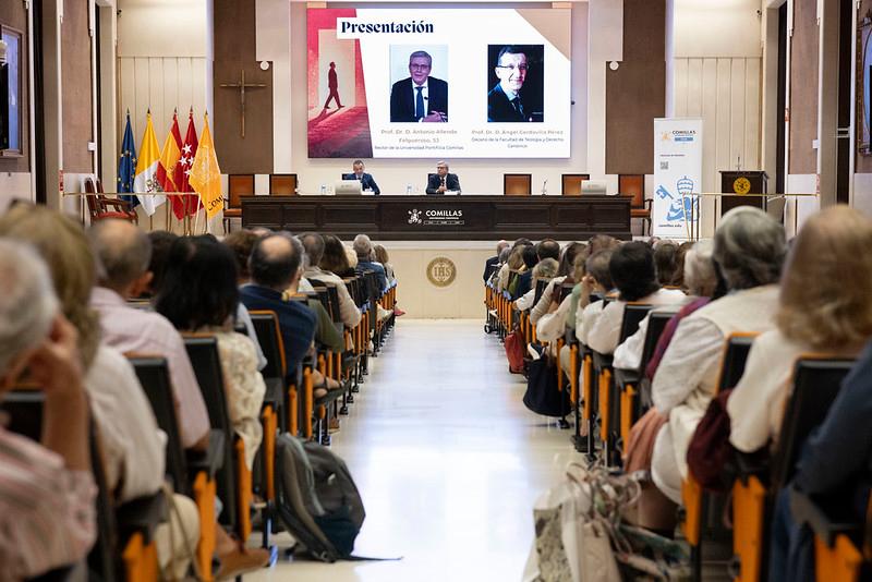 Una conferencia con un público atento en un auditorio, donde dos ponentes están presentando en el escenario.