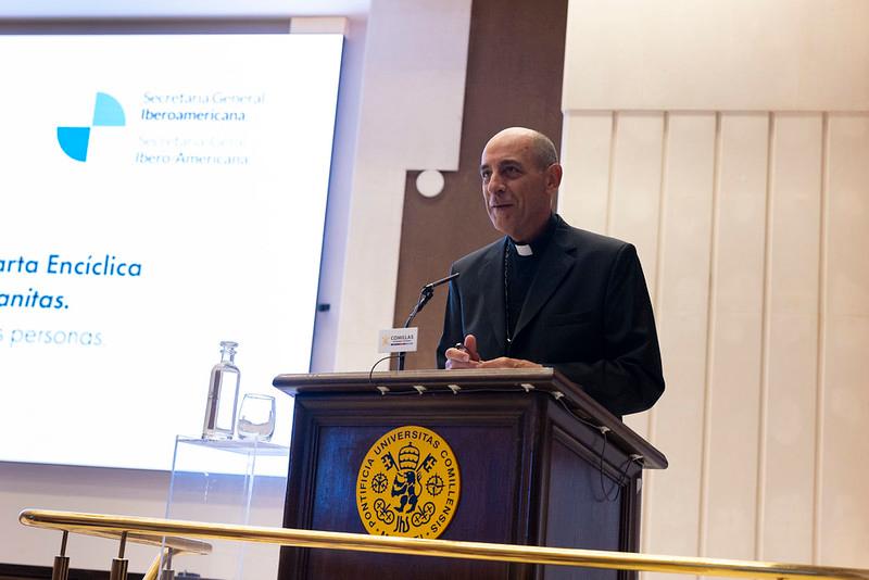 Un sacerdote habla desde un podio en un evento relacionado con una encíclica.