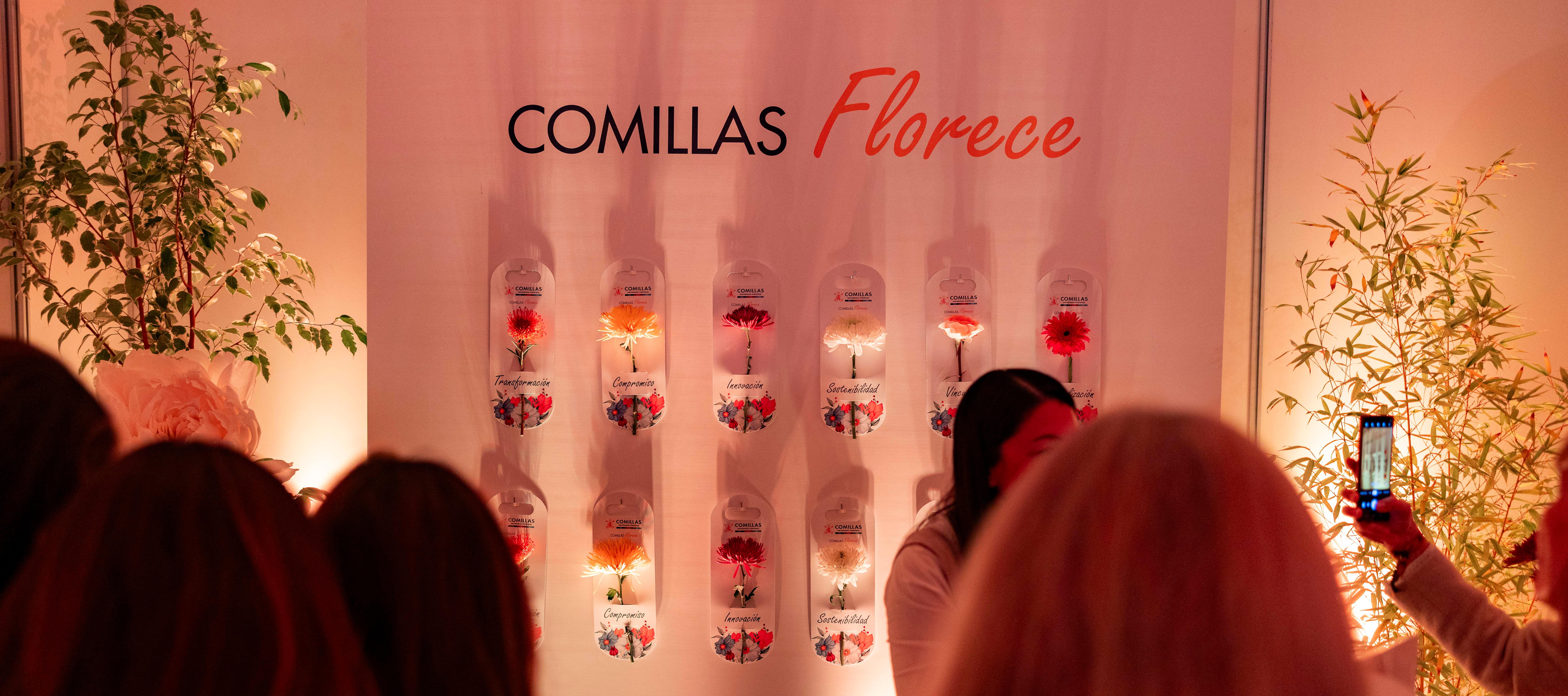 Una exhibición en Comillas con flores decorativas y un fondo que dice 'Comillas Florece'.