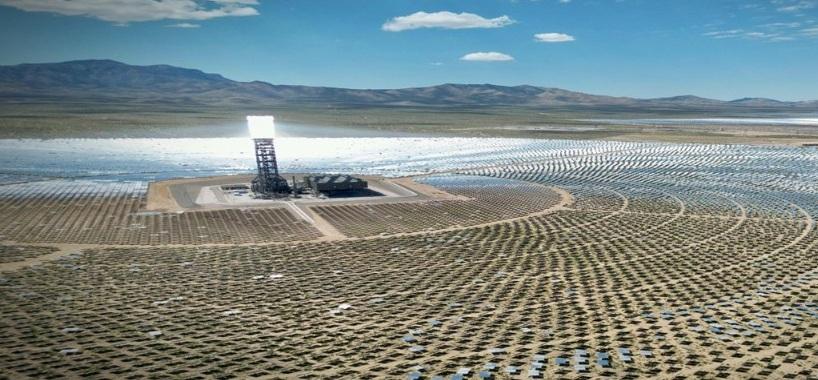 Vista aérea de un campo solar con paneles dispuestos en círculos alrededor de una torre de concentración solar.