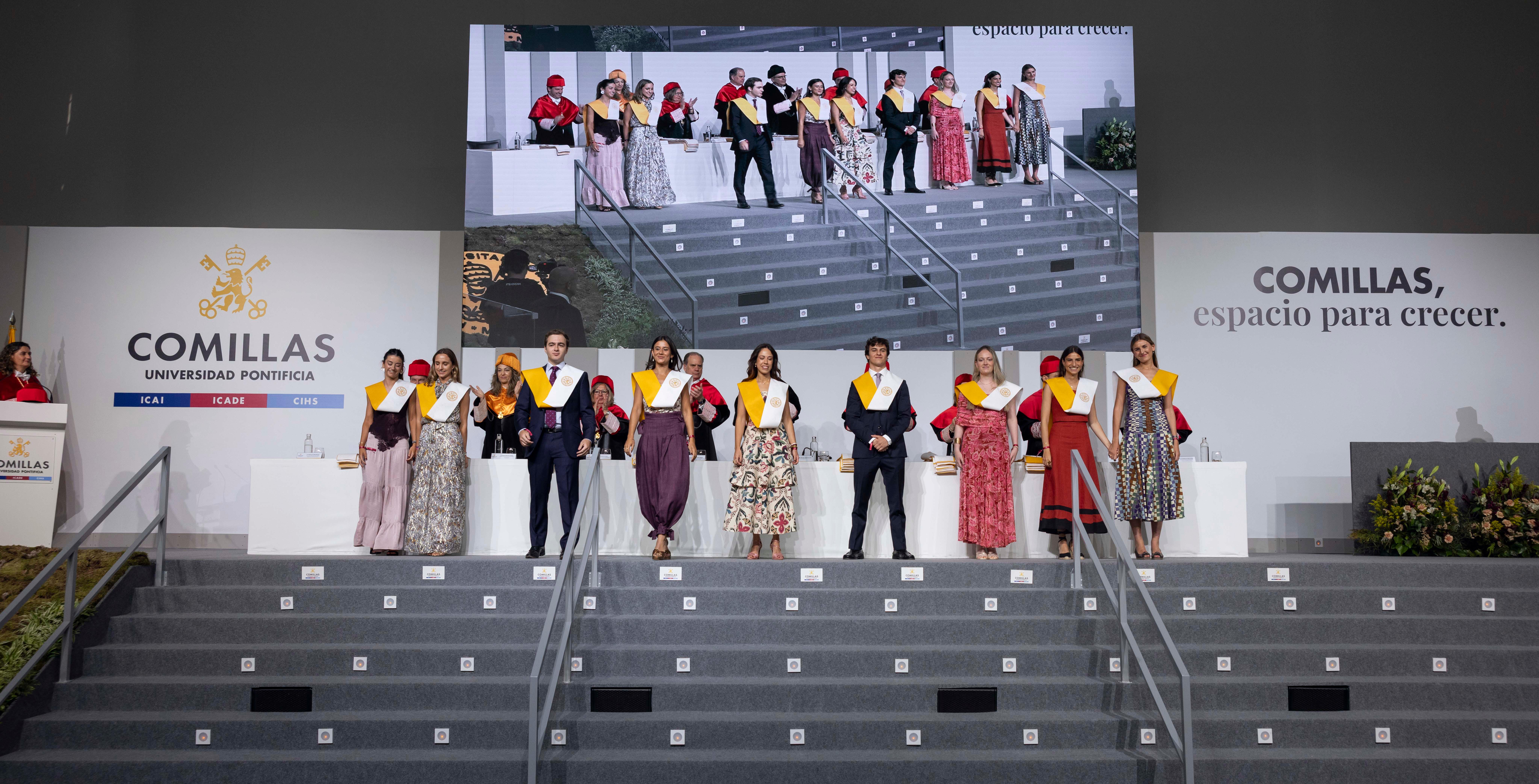Celebración de graduación en la Universidad Pontificia Comillas con varios graduados en el escenario.