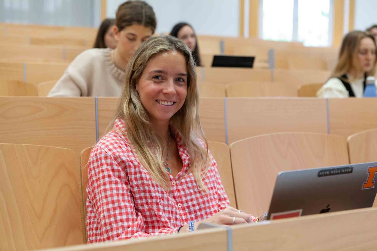 Alumna icade en clase sonriendo