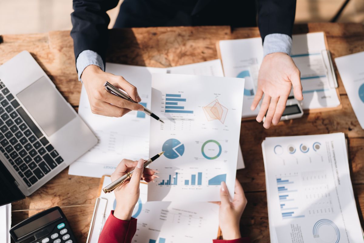 Un grupo de personas analizando gráficos y documentos en una mesa de trabajo.