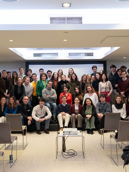 A large group of young adults posing for a photo in a conference room with chairs and a presentation stand.