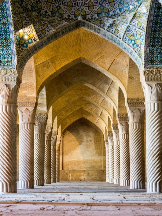 Un interior de columnas con arcos en un edificio monumental que destaca por su arquitectura islámica.