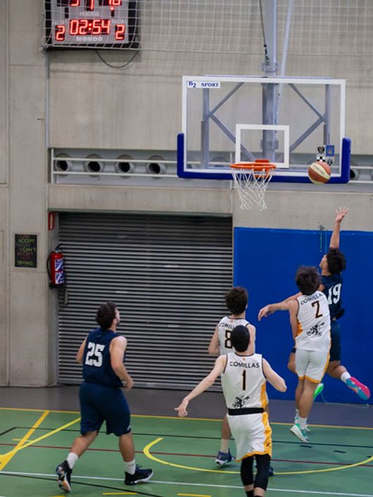 Un grupo de jugadores de baloncesto compite en una cancha cerrada.