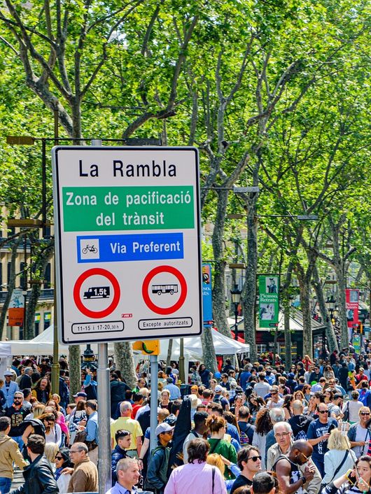 Una bulliciosa calle en La Rambla, llena de gente y rodeada de árboles y edificios.