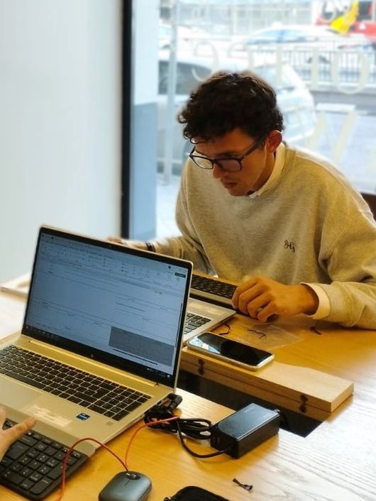 Dos personas trabajando en computadoras portátiles en una mesa.