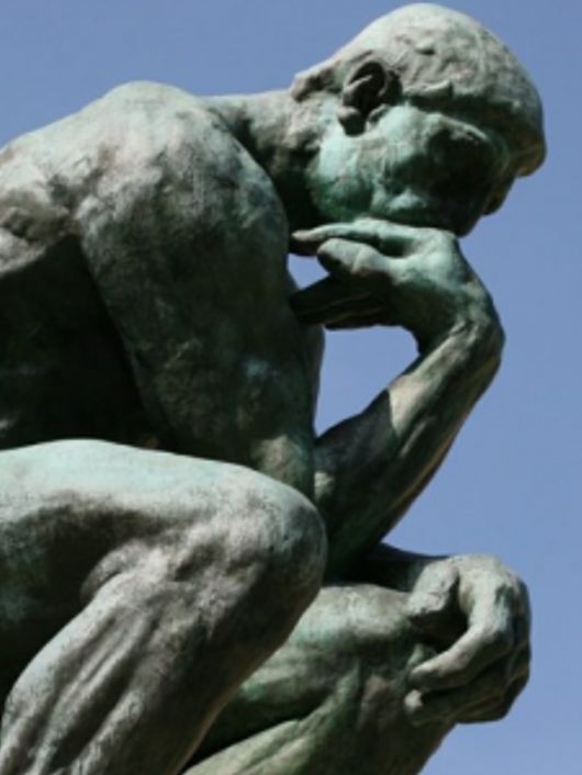 Una escultura de un hombre pensativo en una pose reflexiva.