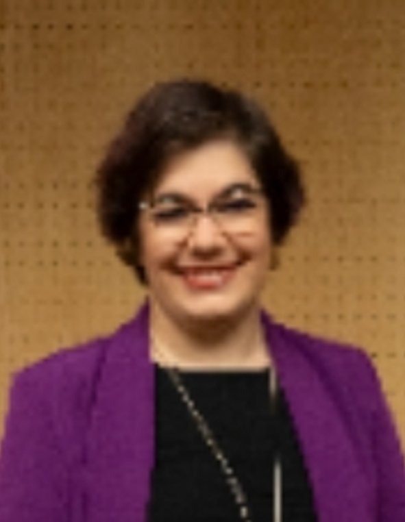 Una mujer sonriente con cabello corto y una chaqueta morada.