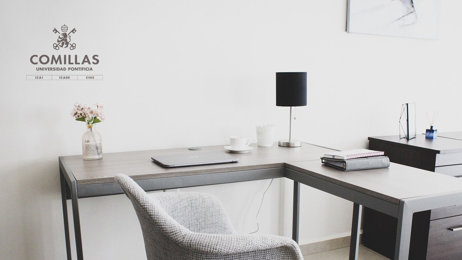 Una oficina moderna y minimalista con un escritorio, una lámpara y una planta en un jarrón.