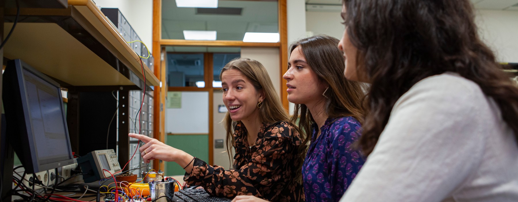 Tres mujeres trabajan juntas en un laboratorio frente a una computadora.
