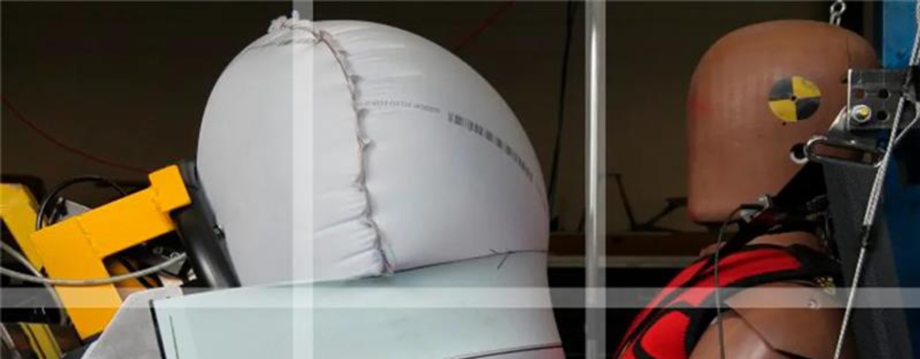 La imagen muestra un maniquí de pruebas de choque con un airbag desplegado.