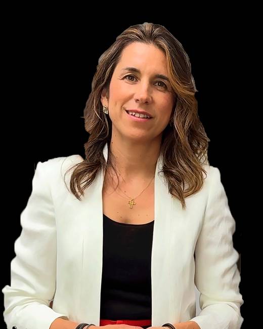 Mujer con blusa negra y chaqueta blanca, sonriente y posando ante un fondo negro.