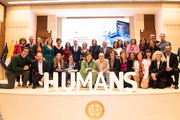 Un grupo de personas posando frente a una gran palabra que dice 'HUMANS' en un evento formal.