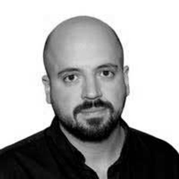 Retrato en blanco y negro de un hombre con cabeza rapada y barba, mirando a la cámara.